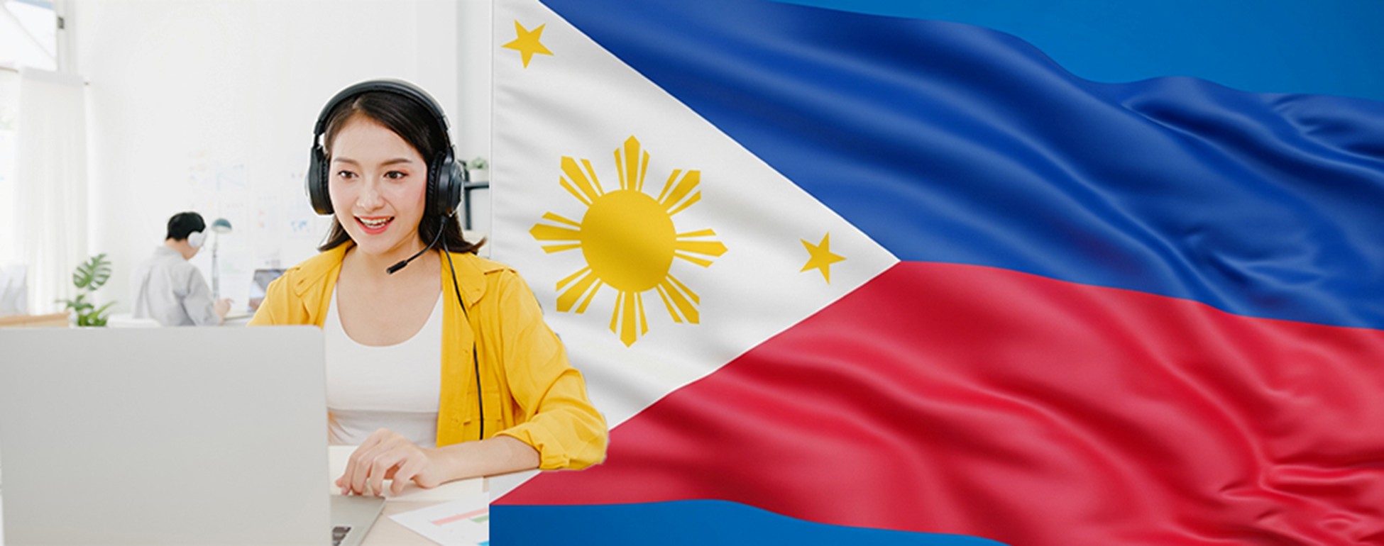 A woman smiles while working on a laptop, with the Philippine flag prominently displayed in the background. 